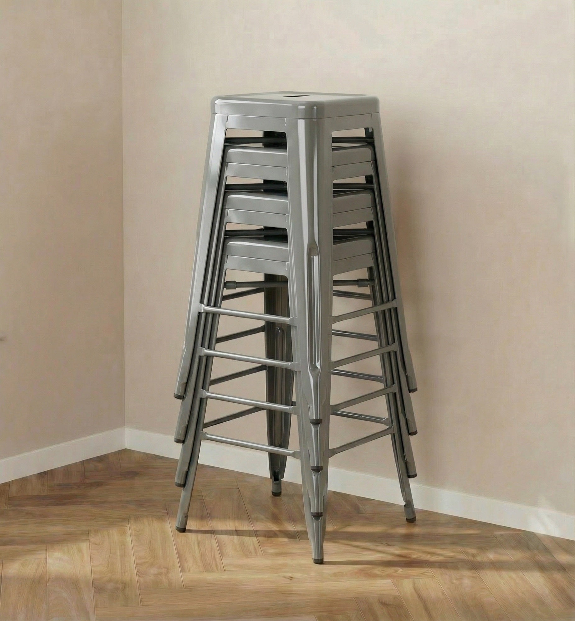 Stack of metal stools against a beige wall.