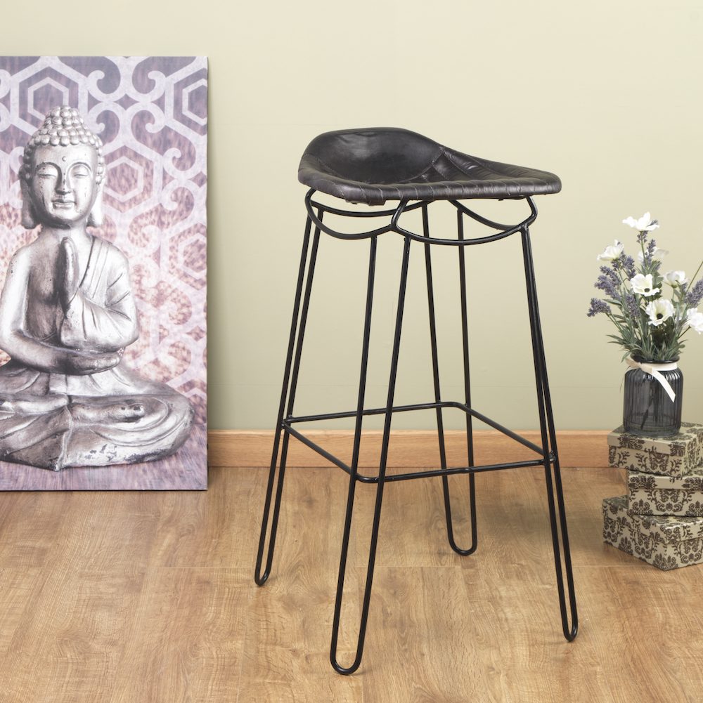 Bar stool with black leather seat in a room with a Buddha statue painting and decorative items.