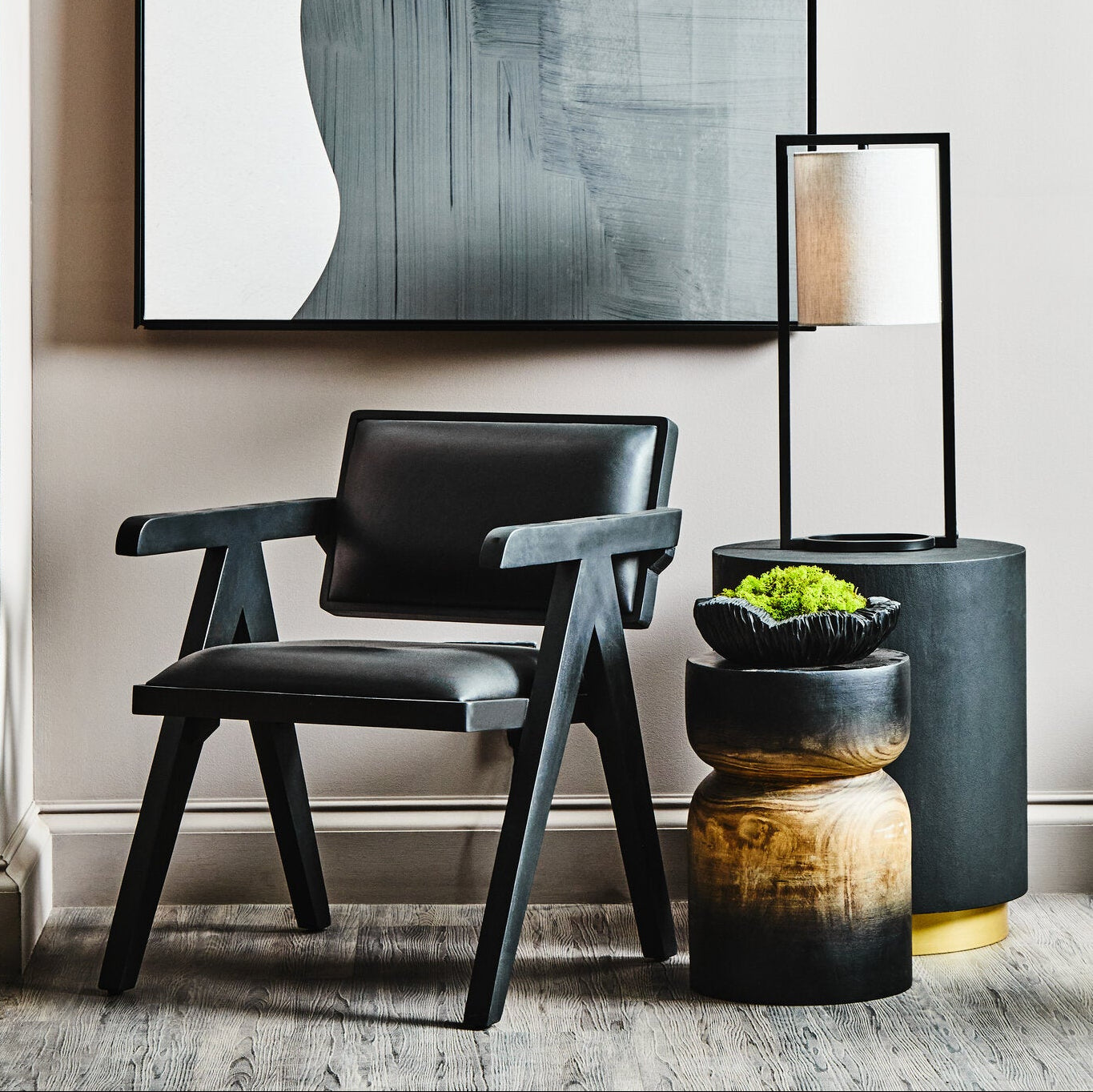 Modern interior with abstract art, black chair, and decorative plants.