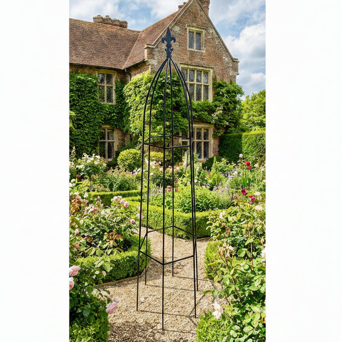 Decorative metal garden obelisk in a lush garden with a historic building in the background.