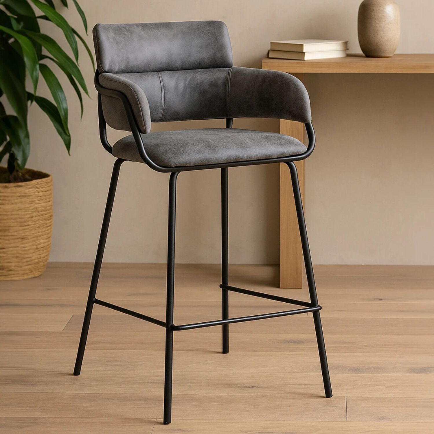 Gray bar stool with black legs in a room with a wooden table and plant.
