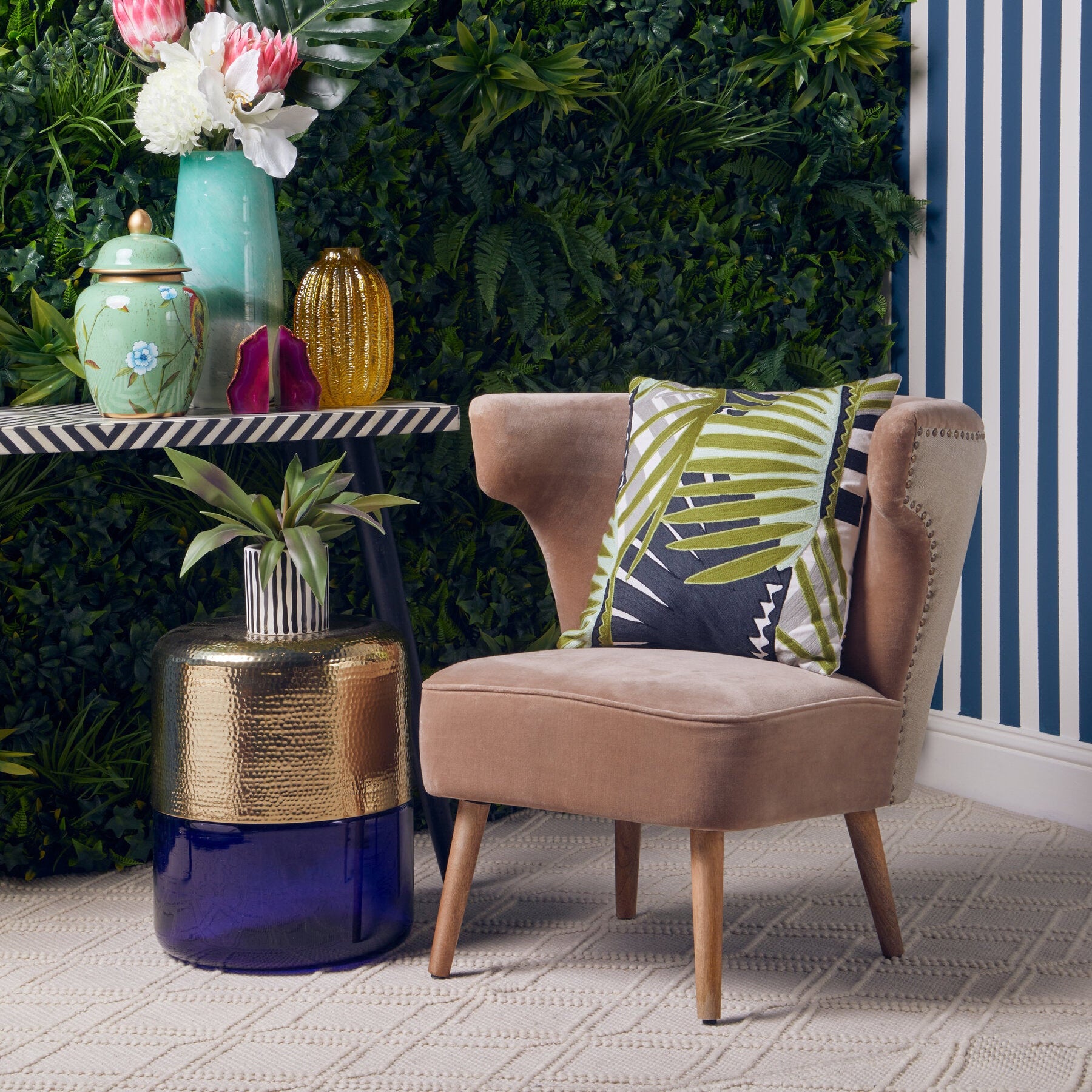 Decorative room setting with a chair, table, and floral arrangement against a green wall.